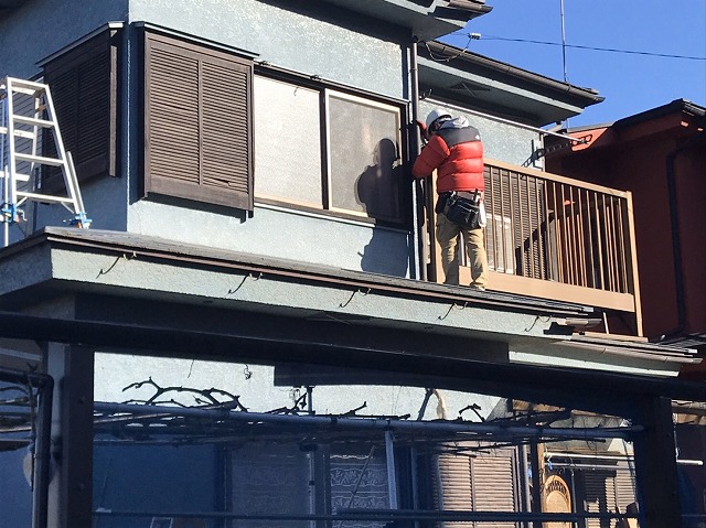 下屋根に立ち竪樋を補修する職人