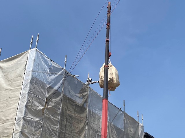 屋根上のスタッフが指示しながらフレコンバックをユニックで降ろす