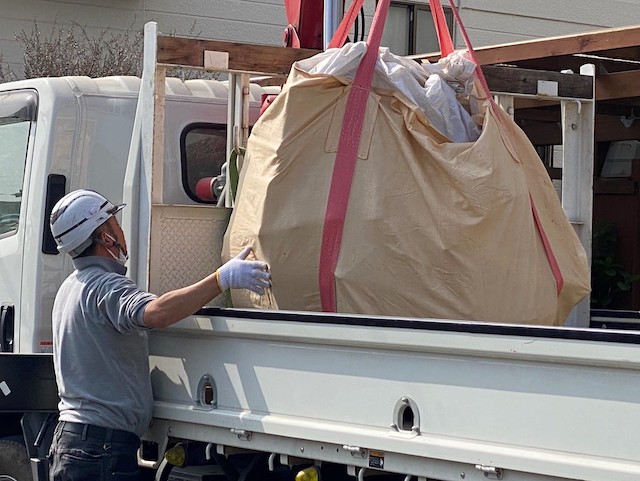 ユニックで吊るしながらフレコンバックをトラックの荷台に着地させる