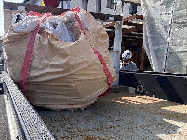 フレコンバックをトラックに誘導するクレーンオペレーター