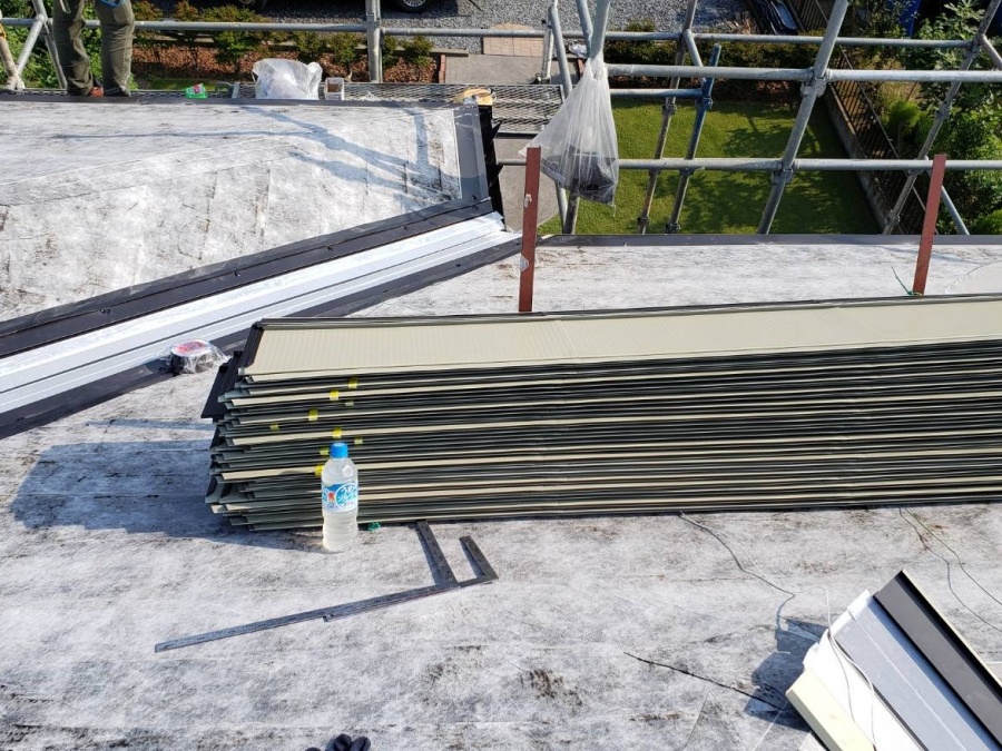 屋根の上に資材止めされて置かれた定尺金属屋根材