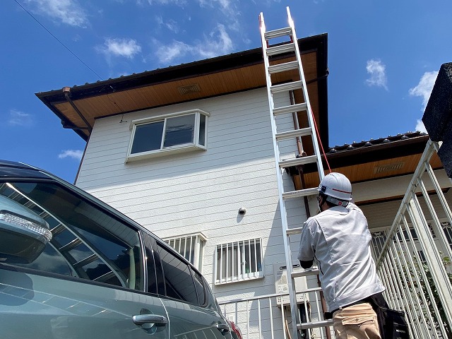 二階の屋根に梯子を設置するスタッフ