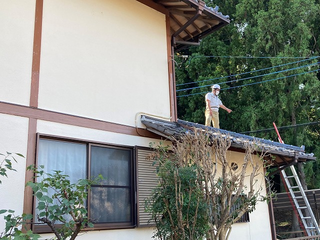 瓦屋根の不具合部を屋根の上から確認するスタッフ