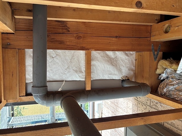 左右のドレンから伸びた排水パイプが片側にまとめられた様子