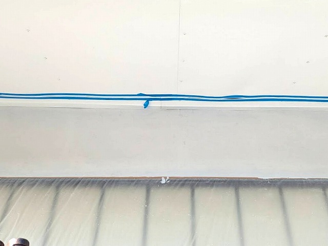 板金を重ね張りした軒天と外壁との境目をマスキングテープで養生