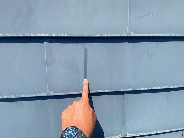 金属屋根を指で触れて塗膜の状態を確認