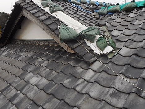 入母屋に葺かれたいぶし瓦に雨漏りシートがかけられている