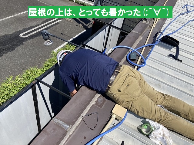 折板屋根に寝そべって調査を行うスタッフ