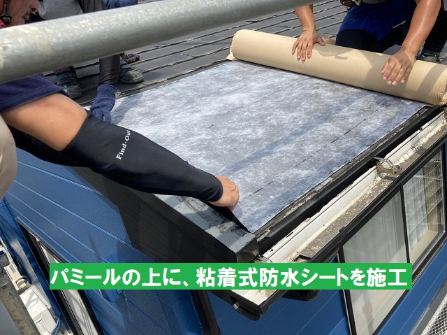 パミールの上に粘着式防水シートを施工する職人