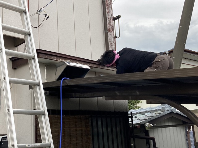 下屋根に登り開口部から霧よけの軒天を覗き込む職人