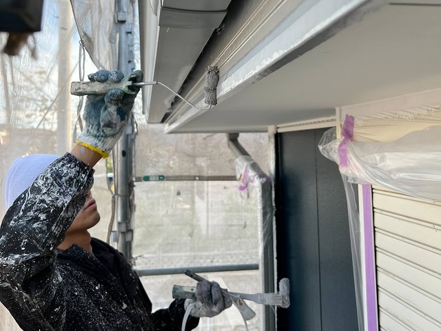 鼻隠し板部分をローラーと刷毛で塗装する職人