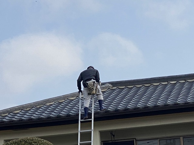 梯子で2階の屋根に登る職人