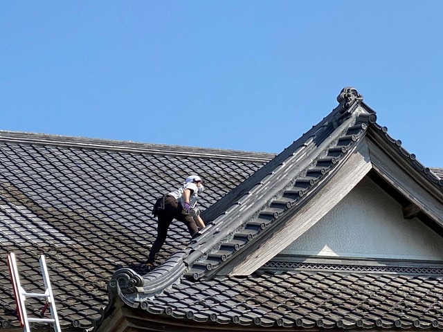 入母屋玄関屋根の急勾配で登るのに苦労しているスタッフ