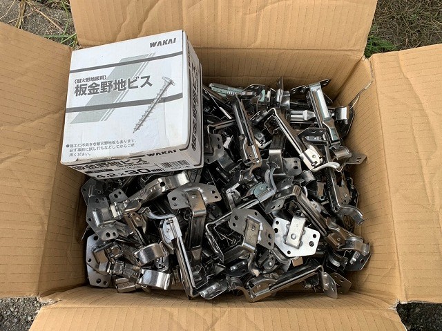 段ボールに入った雨樋用吊り金具と留め具であるビス
