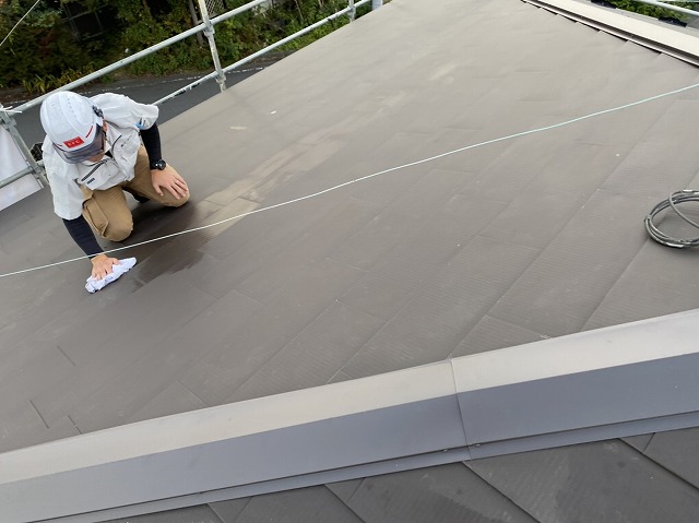 ガルバリウム鋼板でカバー工法した屋根を雑巾で拭き上げるスタッフ