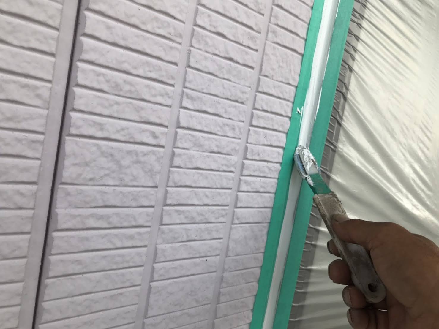 開口部の目地シールをヘラで押える職人の手元