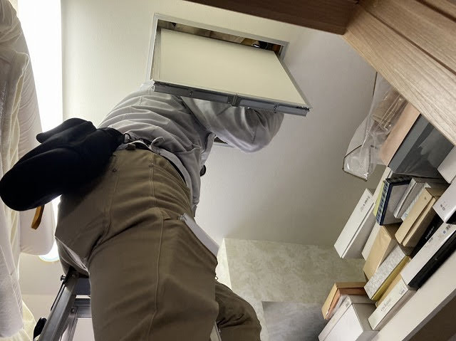 クローゼット内の屋根裏点検口から屋根下地を確認するスタッフ