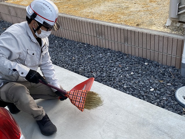 作業時に出たごみを、ほうきで清掃するスタッフ