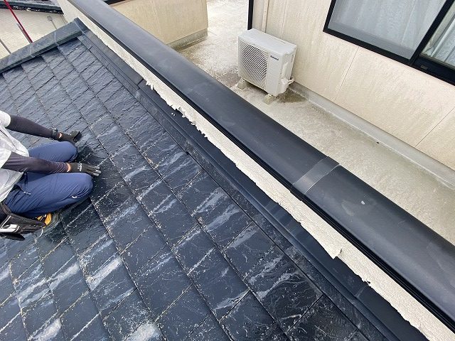 屋根の上からベランダの不具合を確認するスタッフ