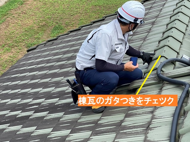 棟瓦のガタつきをチェツクする調査員