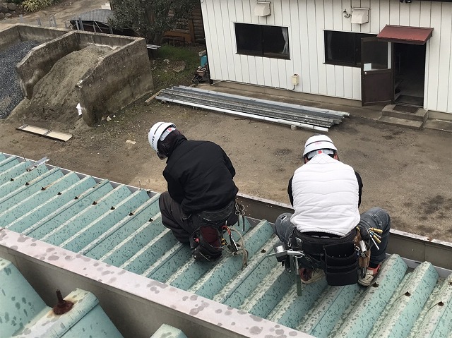 折板屋根のボルトを外す作業員