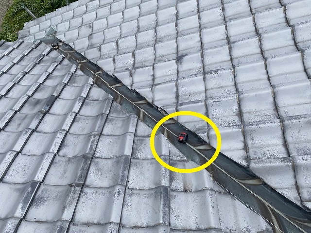 雨漏り原因の谷板金の上にスケルを置く