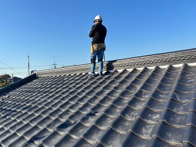 瓦屋根の大棟付近に立つ、瓦職人