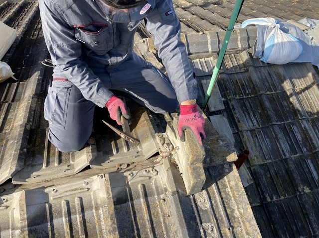 セメント瓦屋根の棟瓦を解体する職人