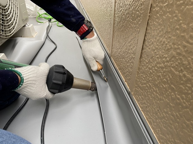 熱温風機でシートを熱溶着する職人