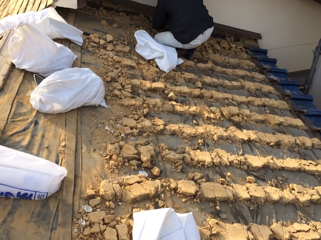 古い防水紙の上に残った葺き土を丁寧に清掃・撤去する宇治市の屋根工事の工程。