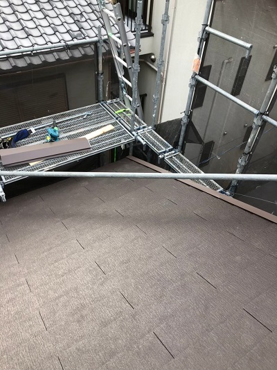 屋根工事用の足場と昇降階段。安全ネットが設置された高所作業現場。