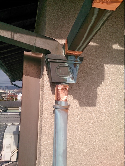 銅製雨樋の集水器下部と縦樋の継ぎ目を銅テープで補修した施工写真