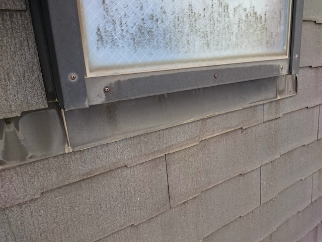 天窓下部の水切り板金周辺の汚れとコケの堆積。排水不良による雨漏りリスク箇所。