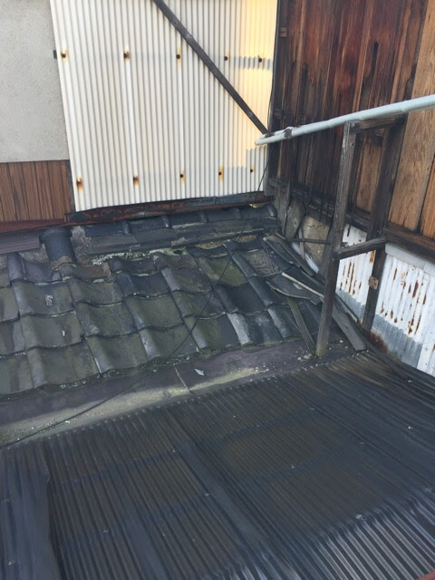瓦のズレを木の板やトタンで強引に補修した城陽市の古い屋根の様子