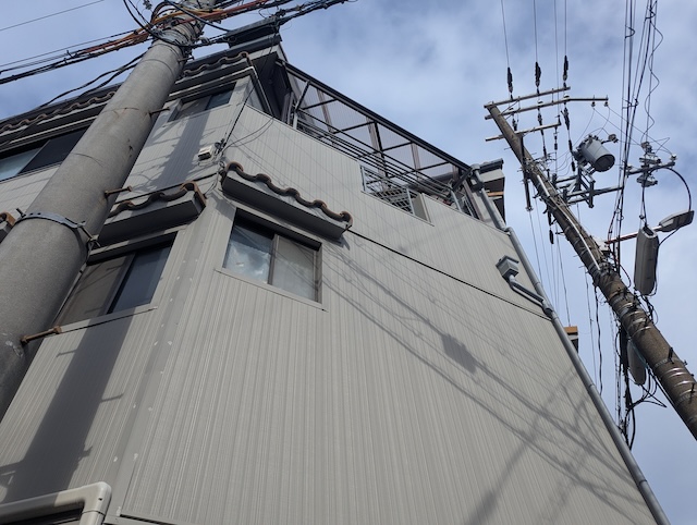 金属サイディング外壁の見上げ画像。窓枠周りのコーキング状況とサイディングの浮き・変形を目視調査。3階建て外装リフォーム後の経過」