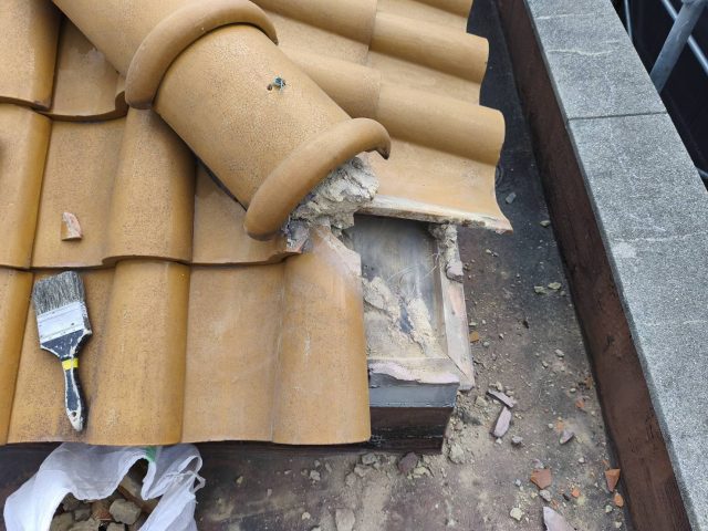長岡京市の屋根修理現場。破損したS瓦を撤去し、露出した葺き土（ふきつち）周辺を清掃して下地調整を行っている様子。