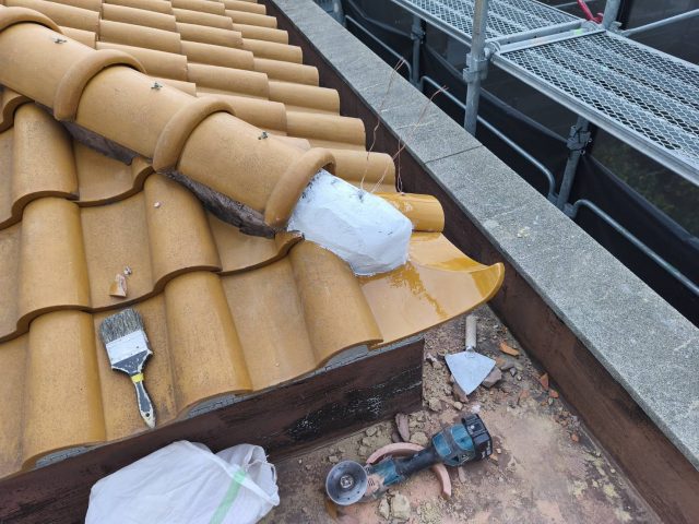 S瓦の隅棟（すみむね）復旧工事。南蛮漆喰で強固な土台を作り、新しい巴瓦を固定するための緊結線（銅線）を準備している工程。