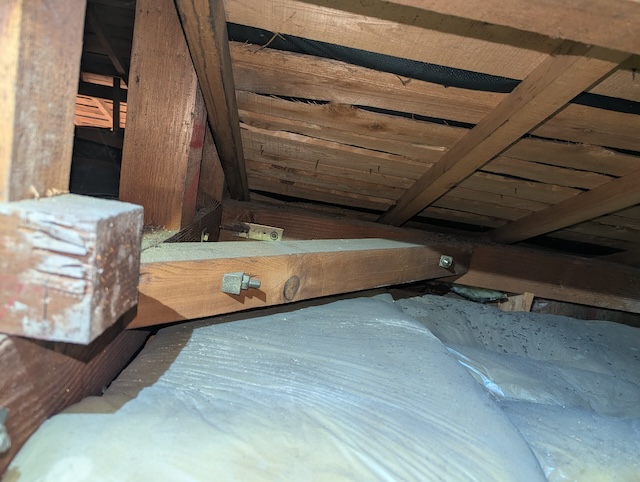 小屋裏（屋根裏）の点検状況。構造材である梁（はり）やボルトの締まり具合、断熱材の状態を目視確認。