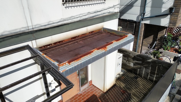 テラス（庇）部分の金属屋根と破風板の著しい腐食。塗膜が完全に剥がれ落ち、鉄部が露出して赤錆が一面に広がっている危険な状態。