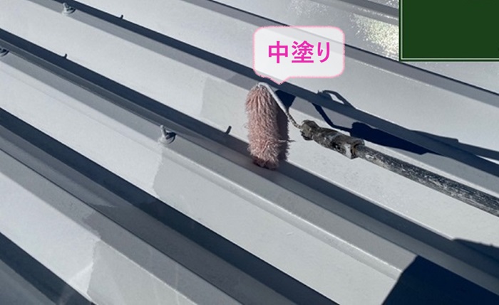 神戸市東灘区の折板屋根のメンテナンス工事で遮熱塗料を中塗りしている様子