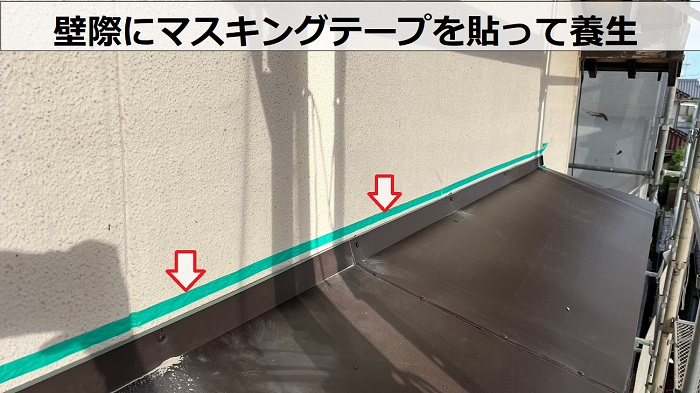 庇屋根の貼り替えで壁際にマスキングテープを貼っている様子
