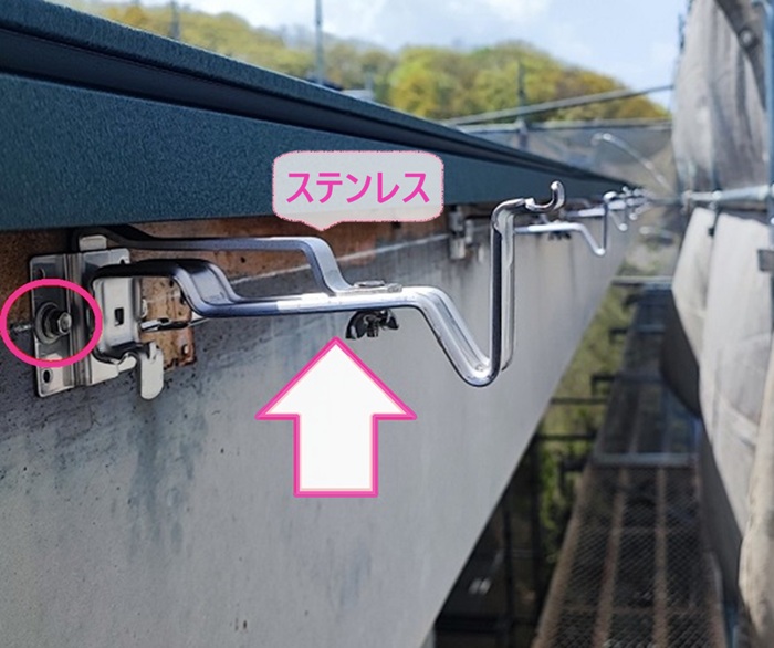テナント建物の大型雨どいリニューアル工事で新しいステンレス製の固定金具を取り付けている様子