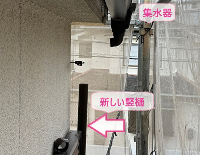 経年劣化した雨どいの交換で集水器と新しい竪樋を取り付けている様子