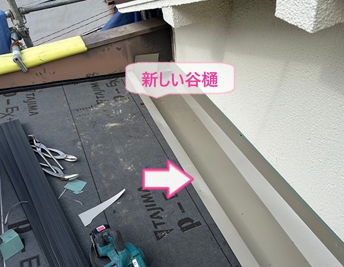 劣化したトタン屋根を重ね葺き改修で新しい谷樋を取り付けている様子