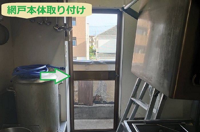 宝塚市で飲食店の厨房にあるアルミ製の勝手口へ網戸を後付けする現場で網戸本体取り付け