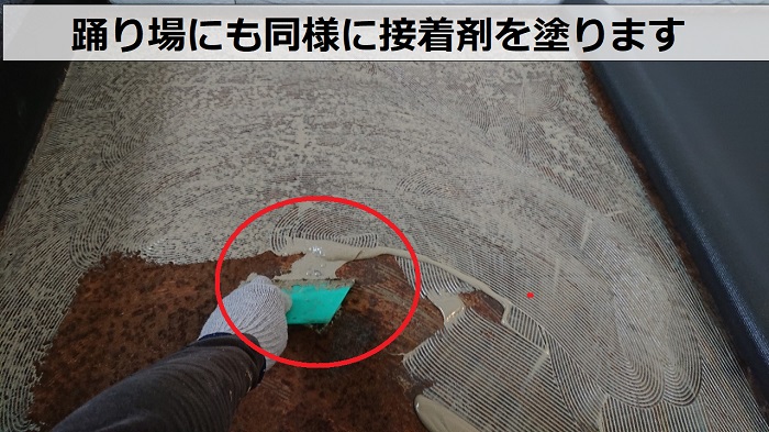 芦屋市で共用階段の踊り場に接着剤を塗っている様子