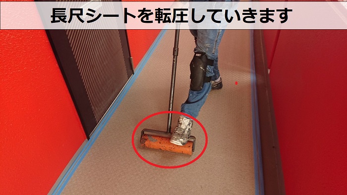 共用廊下の長尺シートを転圧している様子