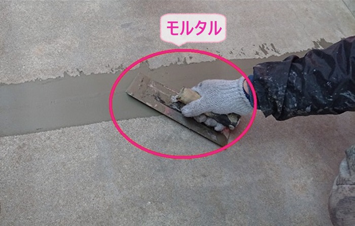 外部階段、廊下のメンテナンス工事で溝をモルタルで埋めている様子