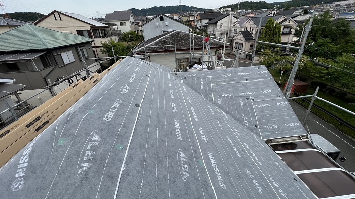 スレート屋根へのカバー工事で防水シートを貼っている様子