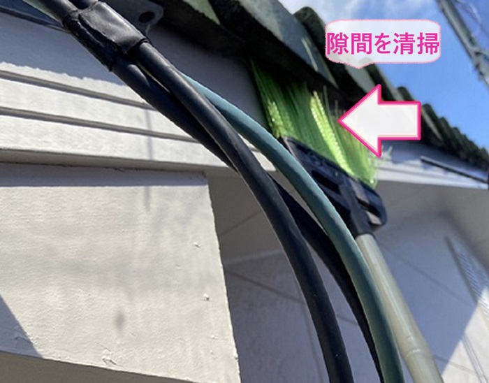 コウモリ侵入防止工事で瓦屋根の隙間をほうきで掃除している様子